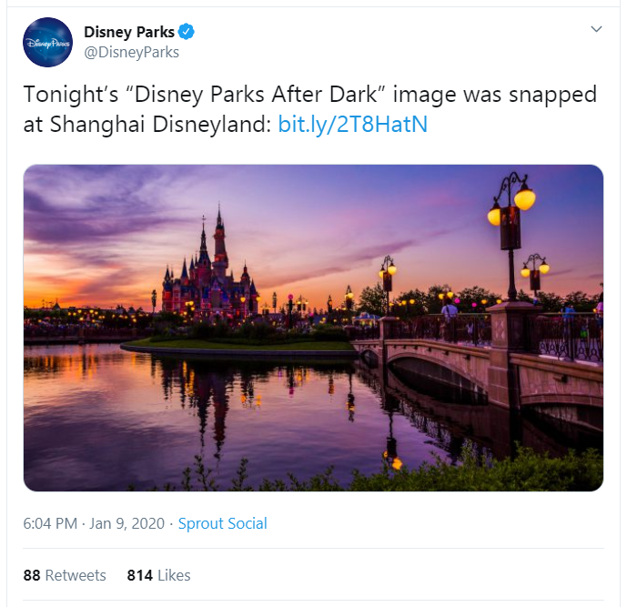 Tweet from Disney Parks @DisneyParks showing a picture of Shanghai Disneyland. Cinderella's castle is lit by the evening light in shades of purple, orange, and yellow.